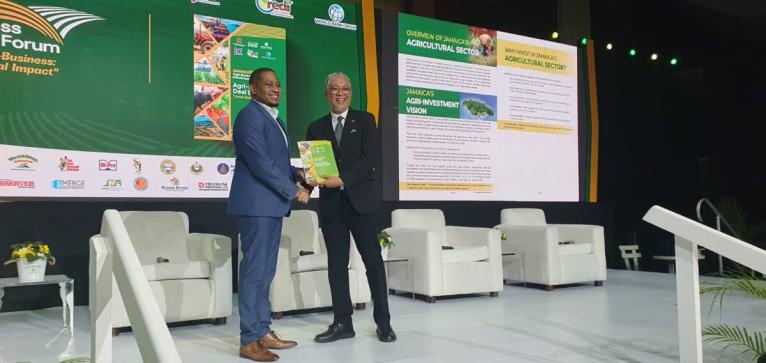 Floyd Green, minister of agriculture, fisheries and mining, receives a copy of the agriculture sector investment deal book from Vivion Scully, chief executive officer of the Agro-Investment Corporation, aimed at attracting Investors. 