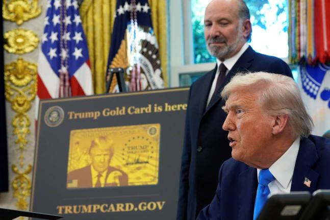 US President Donald Trump speaks as Commerce Secretary Howard Lutnick listens alongside a poster of the Trump Gold Card in the Oval Office of the White House, on Friday, September 19, in Washington. 