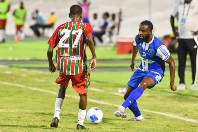Mount Pleasant’s Gadail Irving (right) passes the ball between the legs of Robinhood FC’s Don Turr during their Concacaf Caribbean Cup Match at the National Stadium on August 19.