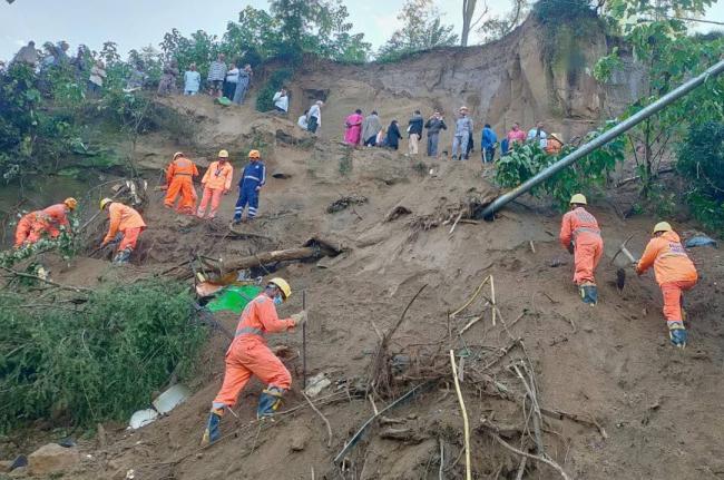 In this handout photo released by the National Disaster Response Force (NDRF), NDRF personnel look for survivors after debris from a massive landslide hit a passenger bus Tuesday night, near Bilaspur in India's northern state of Himachal Pradesh, Wednesday
