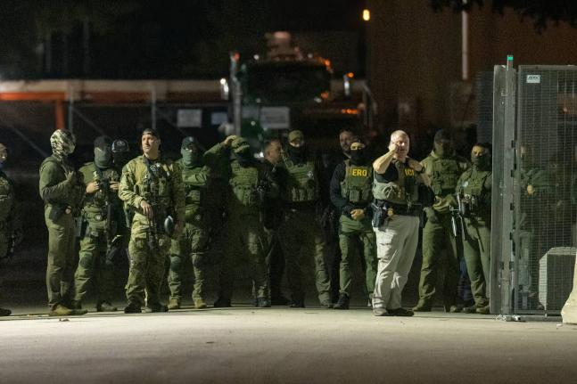 Federal law enforcement officers stand guard in the open gate of the fence built on Beach Street outside the Broadview ICE processing facility in suburban Broadview, Tuesday, October 14, 2025. (Tyler Pasciak LaRiviere/Chicago Sun-Times via AP)
