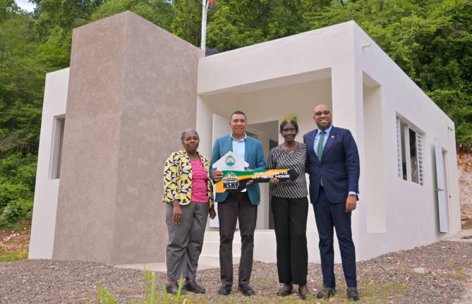 Prime Minister, Dr Andrew Holness (second left) presents New Social Housing Programme (NSHP) recipient Gloria Williams (second right) with a symbolic key during the handover of her new home in Red Hills, St Andrew, on October 15. Sharing in the moment are 