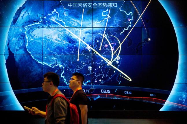 Attendees walk past an electronic display showing recent cyberattacks in China at the China Internet Security Conference in Beijing.