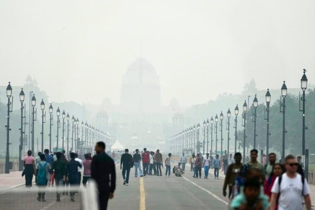 People walk on a street enveloped in smog, in New Delhi, India, on Tuesday, October 28, 2025.