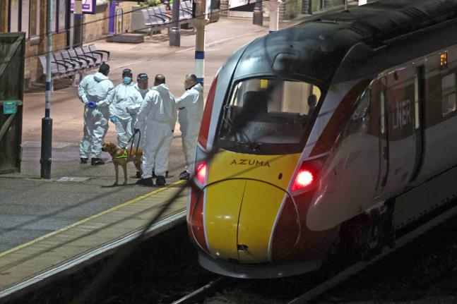 Forensic investigators on the platform by a train at Huntingdon station after a mass stabbing on a London-bound train in Cambridgeshire, England.