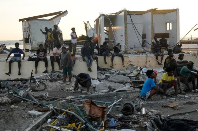 People gather among debris near a bridge in Black River, St Elizabeth, Jamaica, in the aftermath of Hurricane Melissa.