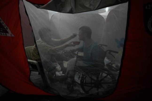 Judy Bertuso (left) feeds her husband Apollo inside a tent at an evacuation centre as Typhoon Fung-wong entered the country on Sunday, November 9 in Quezon city, Philippines.