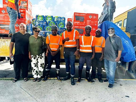 Beverly Nichols (second right) poses with volunteers and the shipment of solar generators and bottled water donated by her Push Start Foundation.