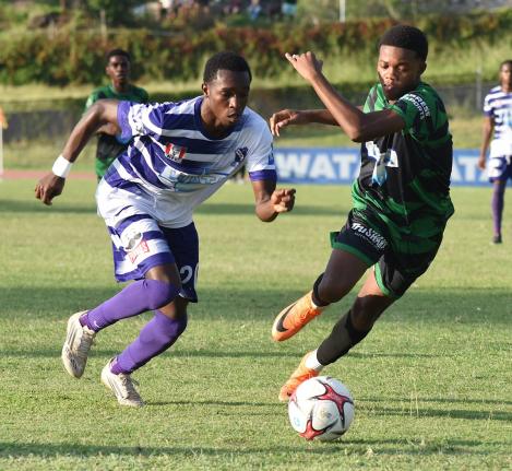Kingston College’s Kajay Fletcher (left) dribbles by Calabar’s Payton Larmond during their ISSA/WATA Manning Cup round-of-16 football match at the Stadium East field yesterday.