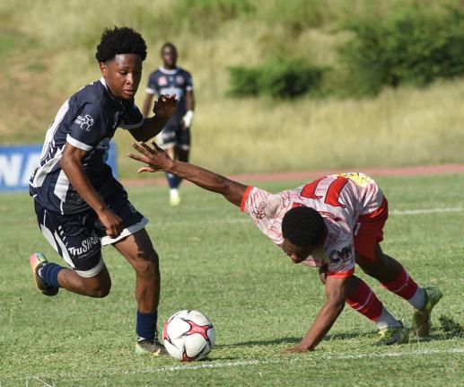 Jamone Lyle (left) of Jamaica College dribbles past Mona High’s Nathaniel McCarthy during their Manning Cup second round match at the Stadium East field on Wednesday. The game ended in a 2-2 draw.