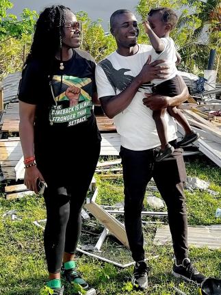 Former national basketballer and Women’s National Basketball Association player Vanessa Gidden poses with Orlando Ennis and his two-year-old son Matthew during a distribution of relief items to residents who were affected by Hurricane Melissa  in Pullet 