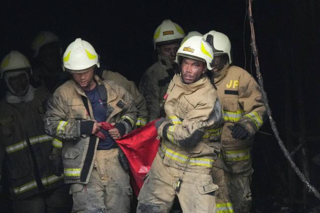 Rescuers carry out the body of a victim from the site of a fire in Jakarta, Indonesia on December 9, 2025. 