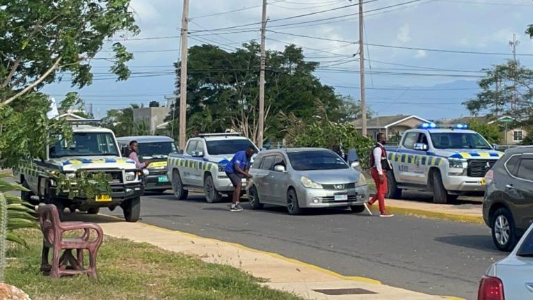Police examine the scene of yesterday’s fatal shoot-out at Phoenix Park Village in Phase 3, Portmore, St Catherine, where a police operation left one alleged robber dead and another on the run. 
