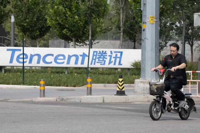 
In this August 7, 2020 photo, a man rides past Tencent headquarters in Beijing, China, on August 7, 2020.