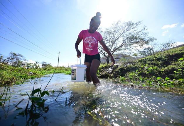 A young woman fills a bucket with water to wash clothes at the Blue Hole along the Sandy Bay main road in Hanover last month as there was no water supply in her community.