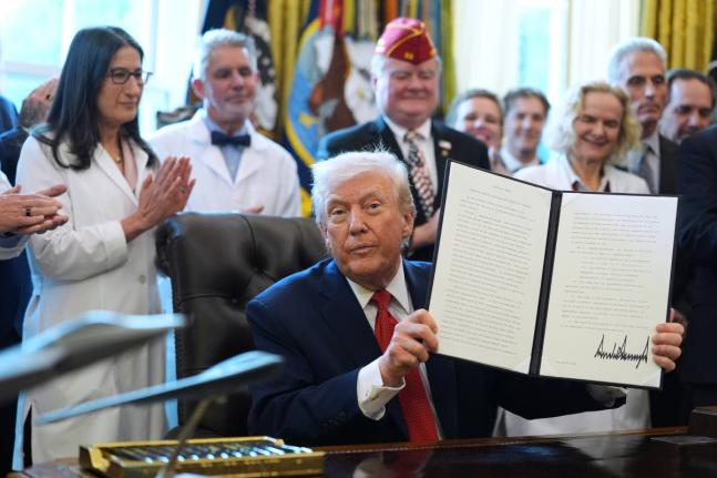 United States President Donald Trump displays an executive order reclassifying marijuana as a less dangerous drug in the Oval Office of the White House on December 18, 2025.