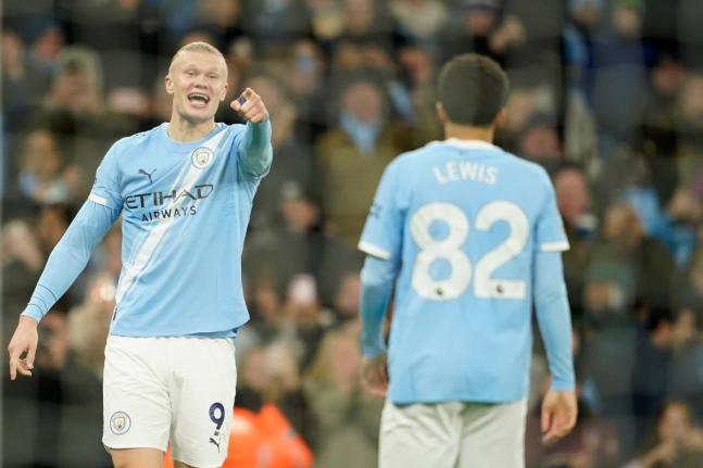 Manchester City's Erling Haaland, left, gestures to teammates Manchester City's Rico Lewis, as he celebrates after scoring his sides third goal of the game during the English Premier League football match between Manchester City and West Ham United in Manc