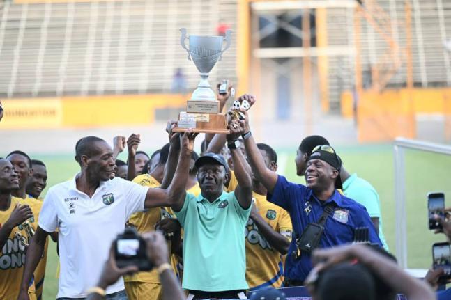 Coach of Clarendon College, Devon Anderson (centre), holds aloft the Ben Francis Cup football trophy after his team defeated Cornwall College 2-1 at the National Stadium on December 20, 2025.