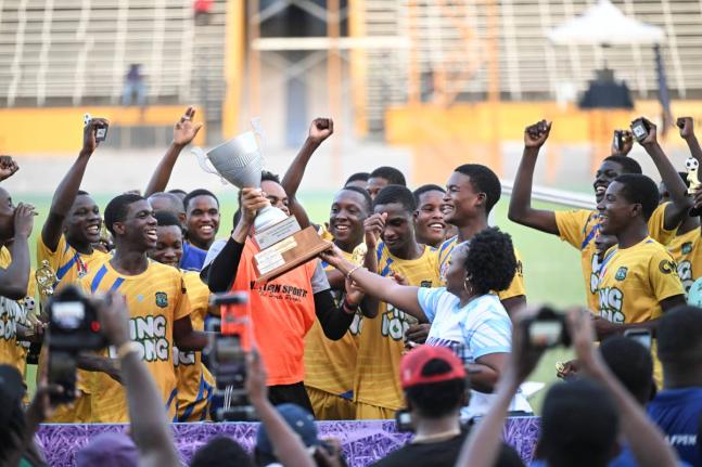
Clarendon College goalkeeper and captain, Lydel Rodney, lifts the Ben Francis Cup title while his teammates celebrate after a 2-1 win over Cornwall College at the National Stadium yesterday.