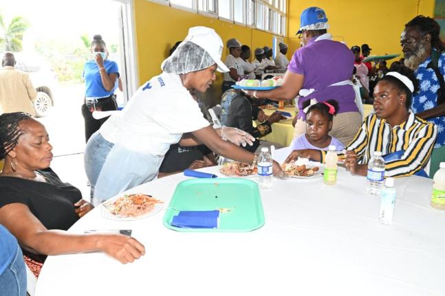 Staff from the Ministry of Justice and Constitutional Affairs serve meals to residents of Hanover during the Ministry's Christmas outreach activity held at Rusea’s High School in Lucea on December 19, 2025.