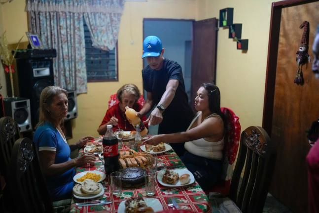 Mariela Gómez (right) and her partner Abraham Castro, a migrant couple, sit for Christmas dinner at Castro’s parents’ home in Maracay, Venezuela.