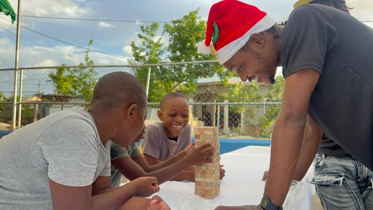 Devon Dallas, of  A-List Marketing and Entertainment Group, engages children in a lively game of Jenga during the ‘Joy to the West’ initiative in Westmoreland. The event brought festive fun and support to families impacted by Hurricane Melissa.