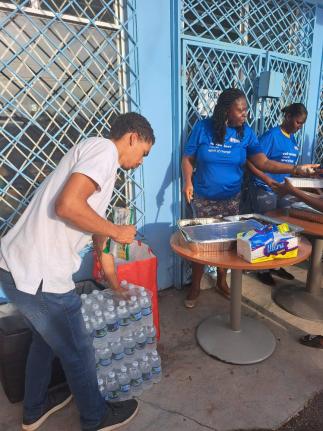 Brian Anderson (left), the president of the National Secondary Students’ Council, works with volunteers in an outreach initiative in Treasure Beach, St Elizabeth, one week after the passage of Hurricane Melissa.