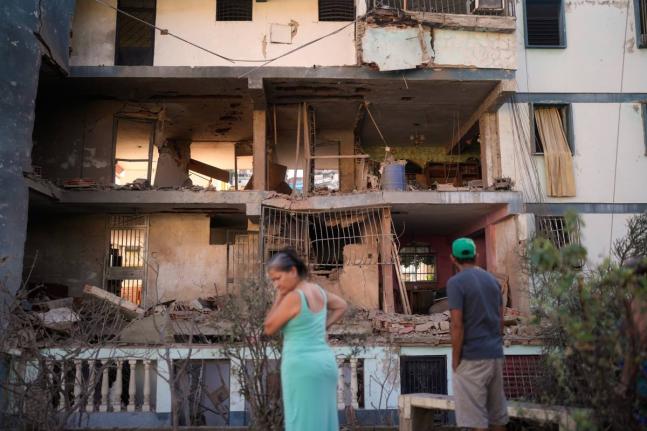 Residents look at a damaged apartment complex that neighbours say was hit during US strikes to capture Nicolás Maduro, in Catia La Mar, Venezuela.