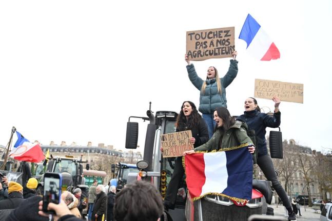 Women atop a tractor support farmers as they protest at the Arc de Triomphe against the European Union's negotiations over the Mercosur trade deal with five South American nations.
