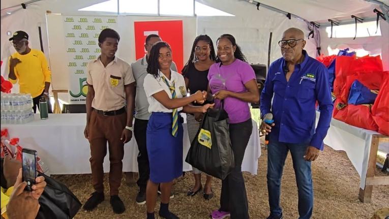 
Jamaica Athletics Administrative Association First Vice-President Ian Forbes (right) looks on as PUMA marketing manager for running, Juliet Campbell, presents a care package to a student from Rusea’s High School at the school’s grounds on Friday.