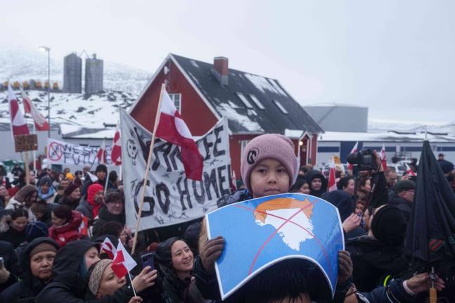 A boy holds a crossed-out map of Greenland topped by a hairpiece symbolising US President Donald Trump, during a protest against Trump’s policy towards Greenland in front of the US Consulate in Nuuk, Greenland