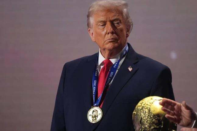 President Donald Trump stands on stage next to the FIFA World Cup after receiving the FIFA Peace Prize during the draw for the 2026 World Cup at the Kennedy Center in Washington, Friday, December 5, 2025.  