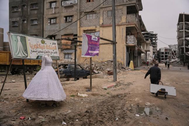 A man walks past a wedding dress displayed on a street next to a bridal shop in Khan Younis, southern Gaza Strip.