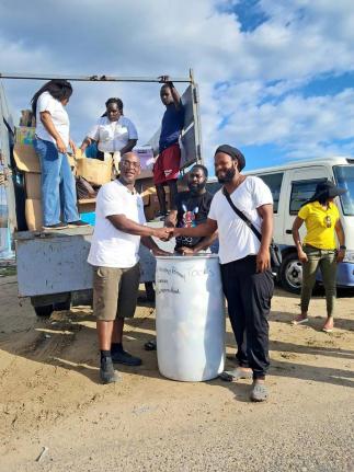 Chief Executive Officer of the Croydon Black Minority Ethnic (BME) Forum, Dr Andrew Brown (left), hands over a barrel of tools and building supplies to community members Michael (centre) and Ridge Harvey (right) in Parottee, St Elizabeth, on January 22. Th