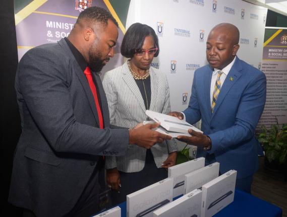 Minister of Labour and Social Security, Pearnel Charles Jr. (right), receives two of the 200 tablet computers donated to the Ministry by the Universal Service Fund (USF) from Chief Executive Officer, Charlton McFarlane. The presentation took place during a