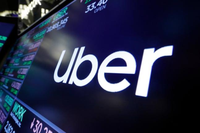 The Uber logo appears above a trading post on the floor of the New York Stock Exchange, August 16, 2019. (AP Photo/Richard Drew, File)