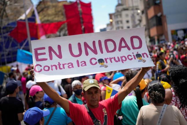 A government supporter holds a sign with a message that reads in Spanish: "In unity against corruption", during a rally against corruption, in Caracas, Venezuela, Saturday, March 25, 2023. (AP Photo/Matias Delacroix, File)