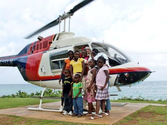 Nine children pose in front of a helicopter with pilot John Morris after they were treated to rides by Island Hoppers Helicopter Tours in St Ann on Christmas Day in 2008.