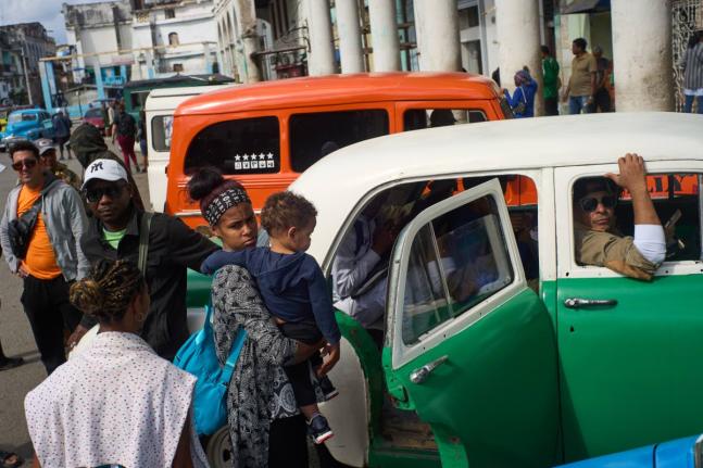 People wait their turns to board shared taxis in Havana, Cuba.