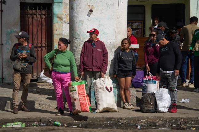 People wait to board transportation in Havana, Cuba.