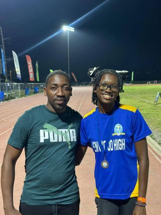 Coach Derol Gardener (left) of Penwood High with his athlete Shakeya Reid minutes after she won silver in the Class 1 100 metres at the recent Corporate Area Championships at the Ashenheim Stadium. 