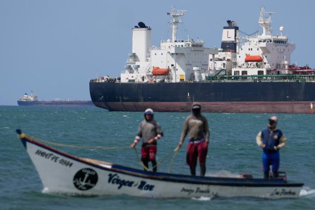 Fishermen pass an oil tanker in the Gulf of Venezuela off the shore of Punta Cardon, Venezuela, January 14, 2026. (AP Photo/Matias Delacroix, FIle)