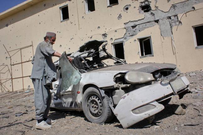 A man inspects a car damaged after a Pakistani strike on a refugee camp in Takhta Pul district, Kandahar province, Afghanistan.