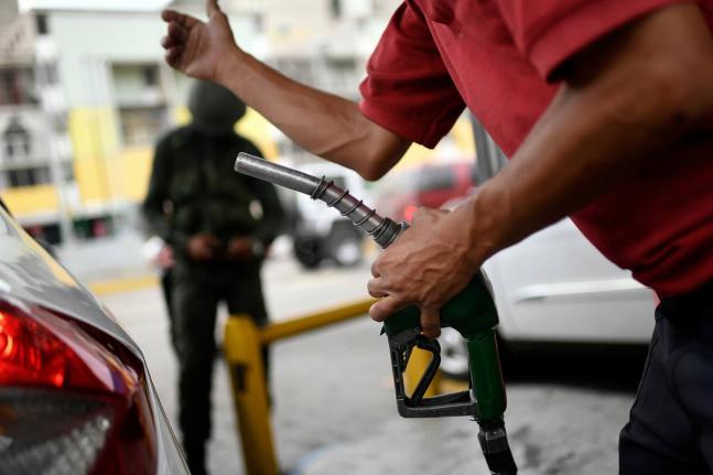 A worker holds a gas pump at a PDVSA state oil company gas station in Caracas, Venezuela, Monday, May 25, 2020. (AP Photo/Matias Delacroix, File)