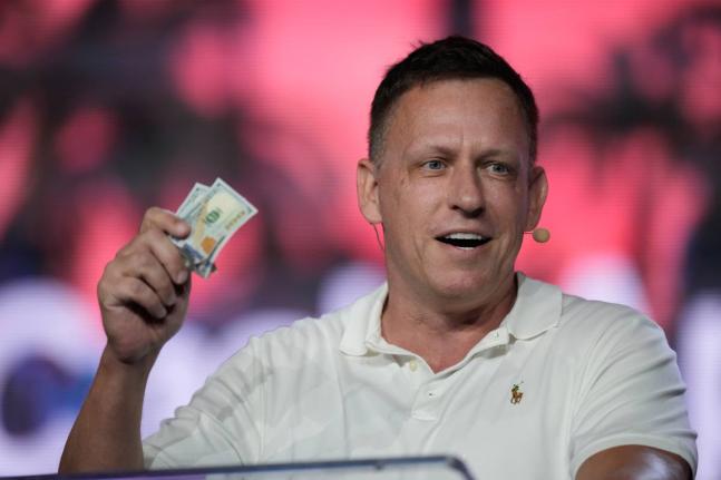 AP 
Peter Thiel, co-founder of PayPal and Palantir, offers a pair of hundred dollar bills to attendees during a keynote address at the Bitcoin Conference, April 7, 2022, in Miami Beach, Florida, USA. 