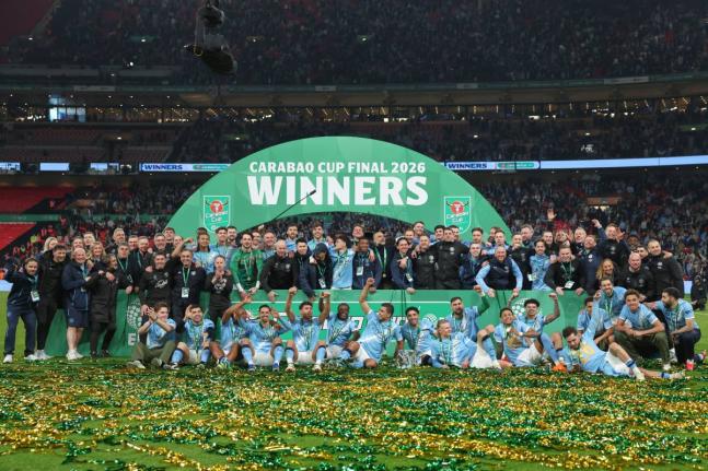 Manchester City players and staff celebrate with the trophy after winning the English League Cup final soccer match between Arsenal and Manchester City in London, Sunday, March 22, 2026. (AP Photo/Richard Pelham)