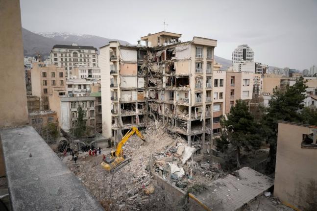 Iranian Red Crescent emergency workers use a bulldozer to clear rubble from a residential building that was hit in US-Israeli strike in Tehran, Iran